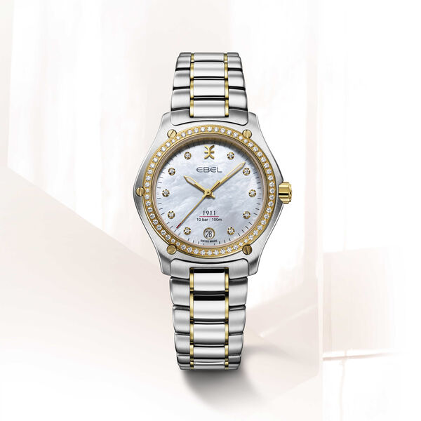 EBEL 1911 - 1216582 dames pols horloge. Edelstalen kast gecombineerd met 18 karaat geel goud. &Oslash; 34 mm. Witte parelmoeren wijzerplaat. Totaal 70 briljanten op wijzerplaat en kastrand ( 0,0431 crt ). Datum aanduiding op 6 uur. Ontspiegeld Saffier glas. Edelstalen band met goud accenten en klap sluiting. Zwitsers quartz uurwerk. 10 ATM waterdicht. Wordt geleverd met een extra kunststof band van gerecycled Ocean plastic.