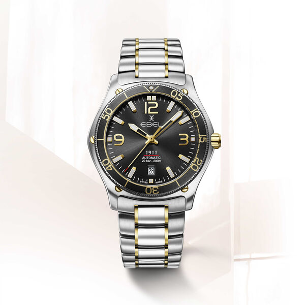 EBEL 1911 - 1216588 heren polshorloge. Edelstalen kast gecombineerd met 18 karaat geel goud met roterende zwarte kast ring Ø 42mm. Zwarte wijzerplaat met met Arabische cijfers en indexen met Super-LumiNova®. Datum venster op 6 uur. Ontspiegeld Saffier glas. Saffier glazen achter deksel. Edelstalen band met klap sluiting. Wordt geleverd met een extra kunststof band van gerecycled Ocean plastic. Zwitsers uurwerk Mechanisch Automaat. 20 ATM waterdicht.