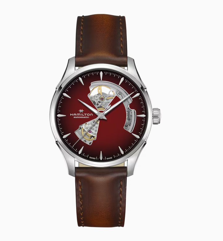 De Hamilton Jazzmaster Open Heart Auto met modelnummer H32675570 is een stijlvol horloge met een automatisch Zwitsers uurwerk. Kenmerken: ronde roestvrijstalen kast, rood analoog wijzerplaat met strepen, saffierglas, en een bruine leren band. Waterbestendig tot 50 meter. Combineer het elegant met formele of smart-casual outfits voor een verfijnde look. De maat van dit horloge is 40mm. 