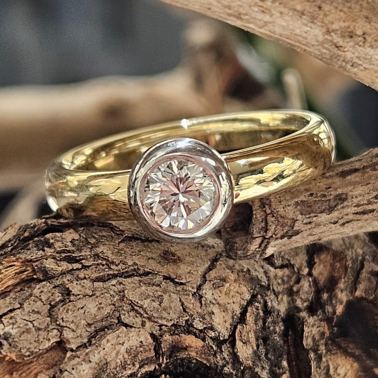 14 karaat speciaal geproduceerde geel- met witgouden ring. Met een briljant in een witgouden Donut zetting op de bovenzijde van de ring gemonteerd. Briljant 0.60 crt. VVS1-F
