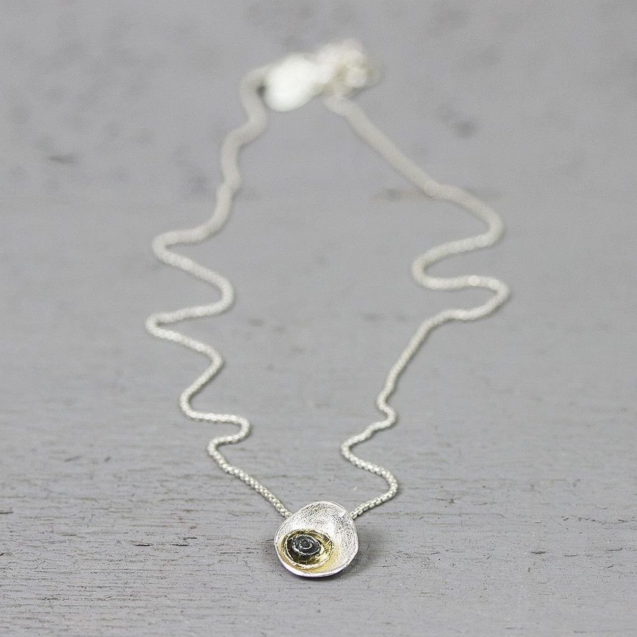 Collier gemaakt van 925 sterling zilver, met daaraan vast een hanger van 925 sterling zilver, geoxideerd zilver en zilver verguld. De hanger bestaat uit 3 verschillende kleuren ronde lagen opgestapeld van groot naar klein. Combineer de hanger met de bijpassende oorstekers.