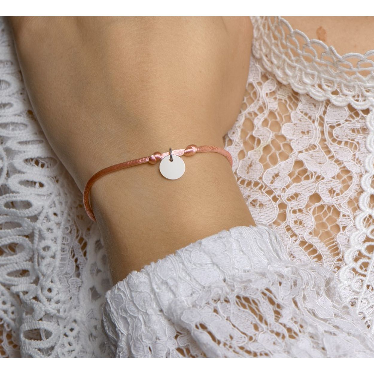 Roze gevlochten armband uitgevoerd met een gerhodineerd 925 zilveren rondje. De armband heeft draaglengtes van 13 tot 26cm. Het rondje heeft een diameter van 10mm.