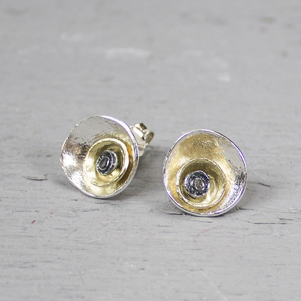 Deze oorstekers zijn gemaakt van 925 sterling zilver, geoxideerd zilver en zilver verguld. De oorhangers zijn cirkelvormig waarin twee kleinere cirkels van zilver verguld en geoxideerd zilver in zijn verwerkt.