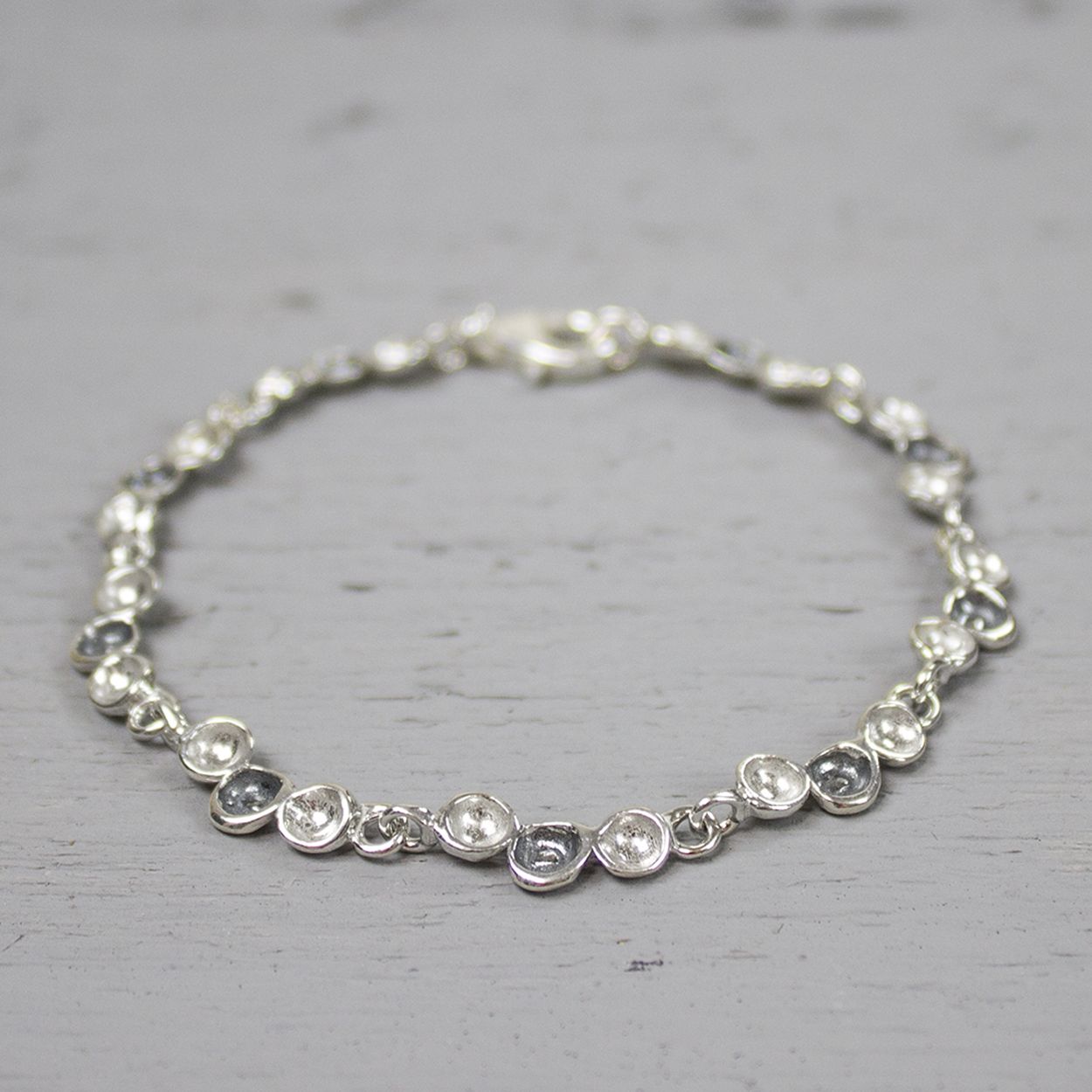 Deze armband bevat schakels bestaande uit drie druppels, waarvan de middelste geoxideerd is.