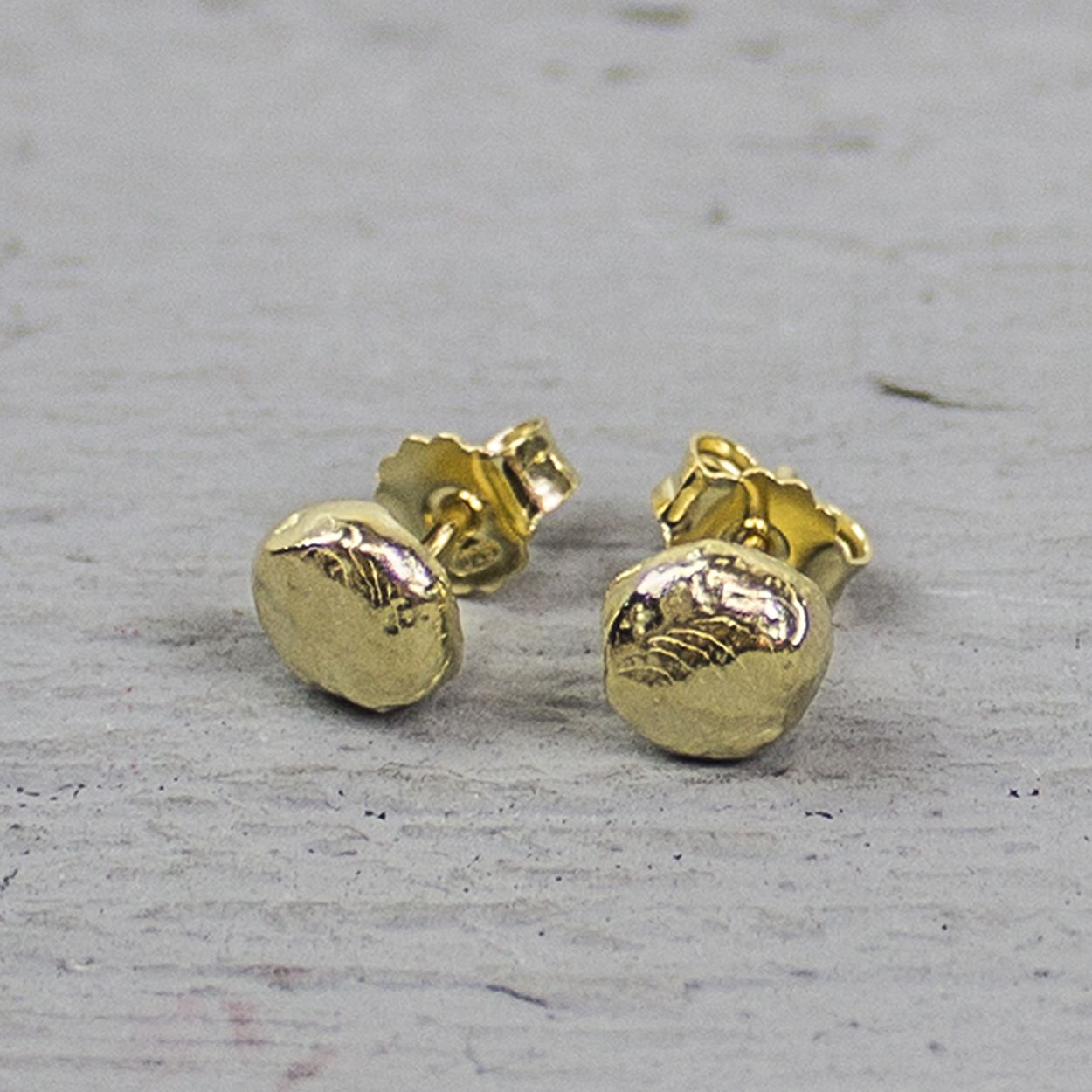 Oorknop rond gemaakt van zilver verguld en bewerkt met hamerslag. Vergulden is het bedekken van een voorwerp met een laagje goud. Dit artikel is door een goudbad gehaald wat ervoor zorgt dat het zilver volledig bedekt wordt met een laagje goud. Resultaat een mooie glanzende afwerking met een laagje echt goud wat ook wel silverplated of goldplated wordt genoemd.