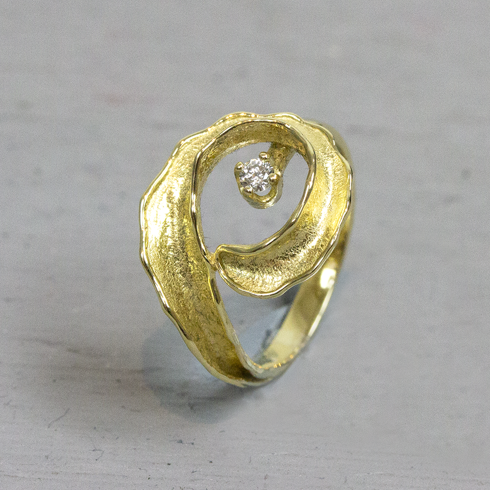 Ring met een gekrulde vorm aan de boven met in het midden een diamant. 0.076ct
