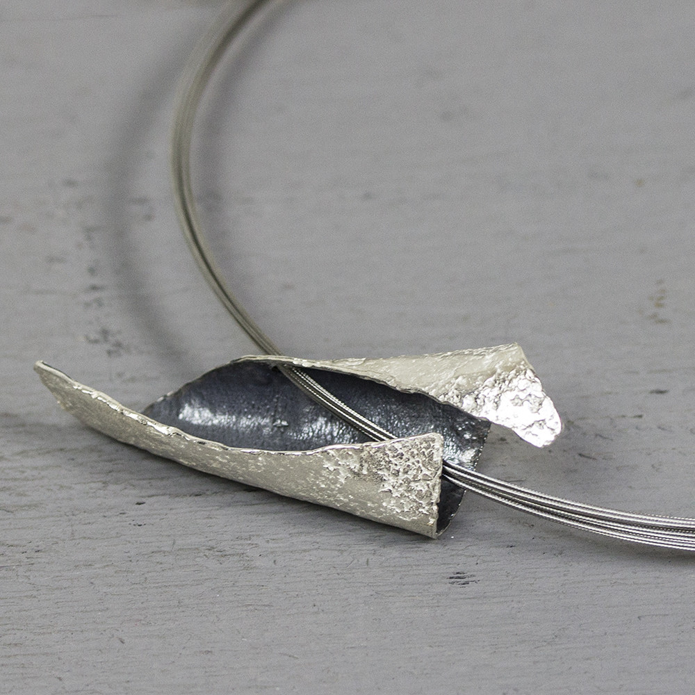 Gevouwen hanger gemaakt van 925 sterling zilver en geoxideerd zilver. Op dit sieraad is gebruik gemaakt van geoxideerd zilver, dit is een oppervlakte bewerking. 


