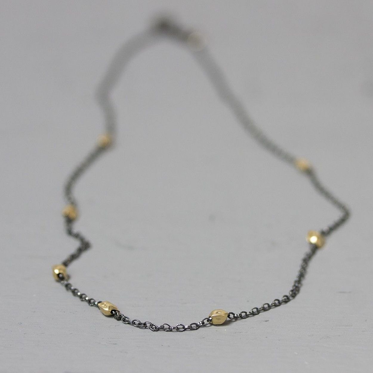 Collier gemaakt van geoxideerd sterling zilver met daaraan symmetrisch balletjes van Goldfilled.