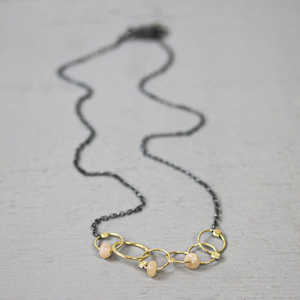 Collier gemaakt van 925 geoxideerd sterling zilver met daaraan cirkels van goldfilled. Aan deze cirkels zitten stukjes roze maansteen.