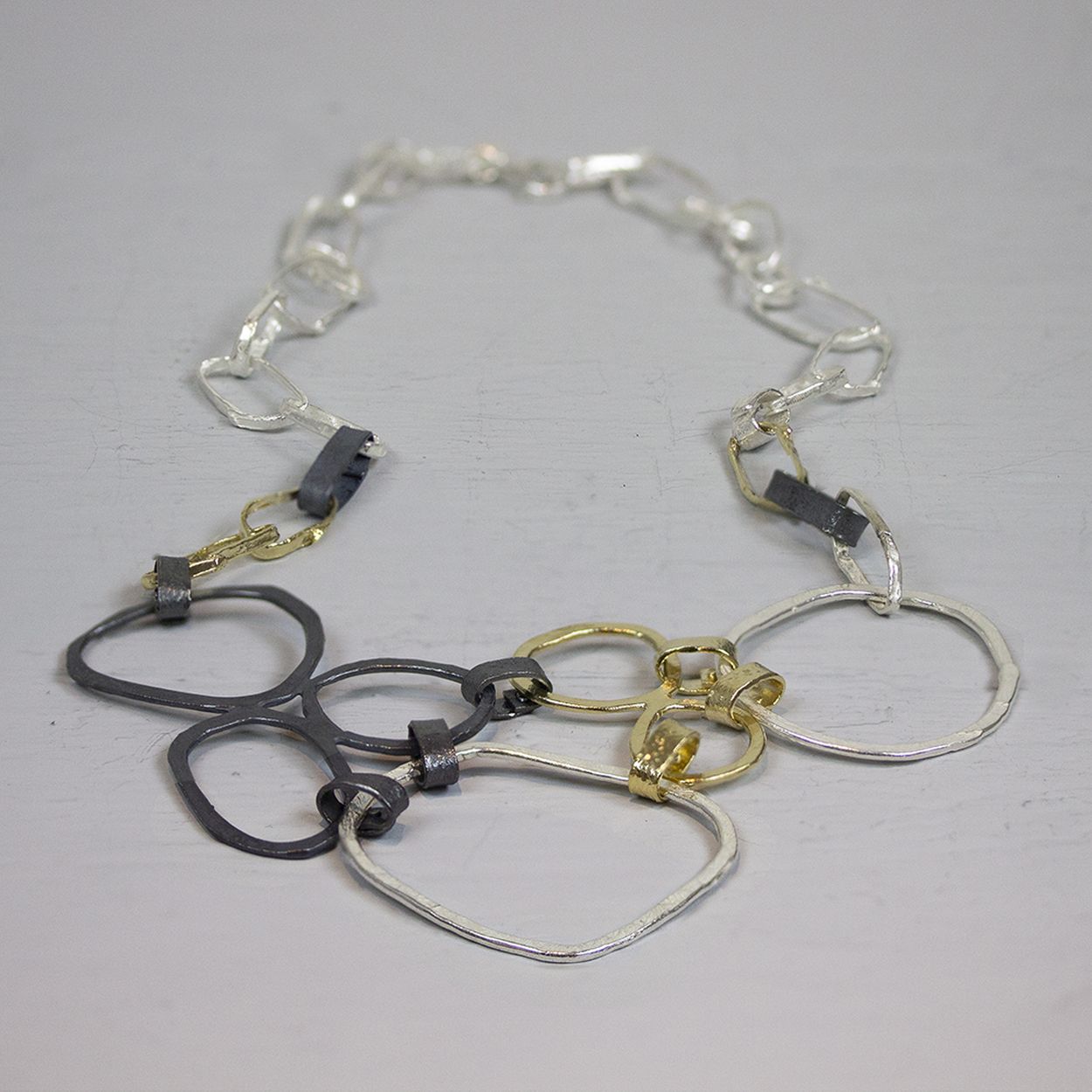 Collier gemaakt van 925 sterling zilver in combinatie met geoxideerd zilver en zilver verguld. Dit collier bestaat uit meerdere grote open schakels in de bekende drie Jeh Jewels kleuren.