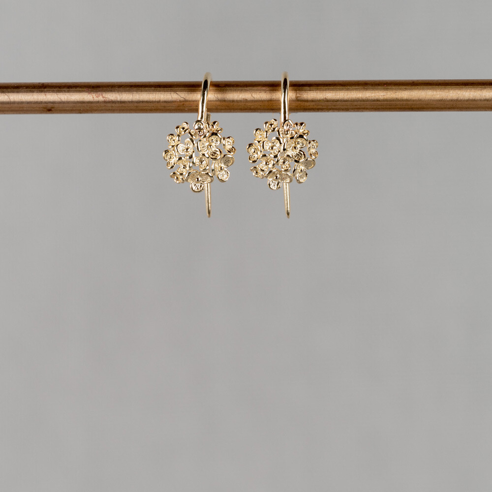 Oorhangers gemaakt van 14 karaat goud, met een dotje bloesem. De gouden sieradenlijn van Jeh is gemaakt van 14 karaats goud. Dit karaatgehalte wordt in Nederland het meest gebruikt, vanwege de hardheid en de kleur. Puur goud is te zacht om draagbare sieraden van te maken, daarom worden er bij metalen gebruikt. Vaak wordt er zilver en koper gebruikt zodat je kunt blijven spreken van 'edele metalen'. Bij 14 karaat goud zijn er van de 1000 delen, 585 delen puur goud. De overige 415 delen bestaan dus uit de overige metalen.