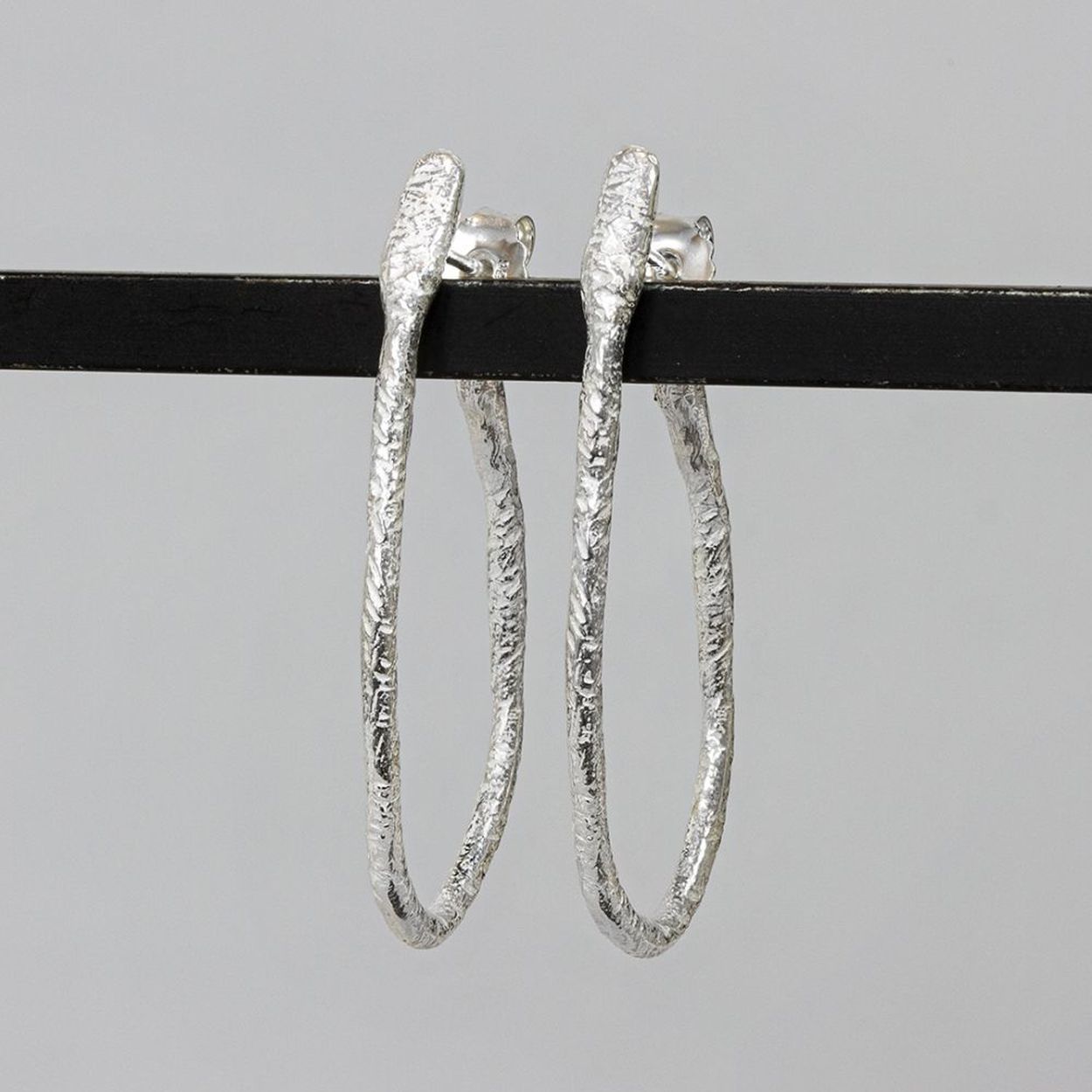 Hoepeloorbel geheel gemaakt van zilver. Deze oorbel is klassiek met een vleugje creativiteit. De vorm is wat speelser dan de klassieke hoepel en ook de afwerking is wat ruwer. Ondanks dat is het een oorbel voor elke gelegenheid.