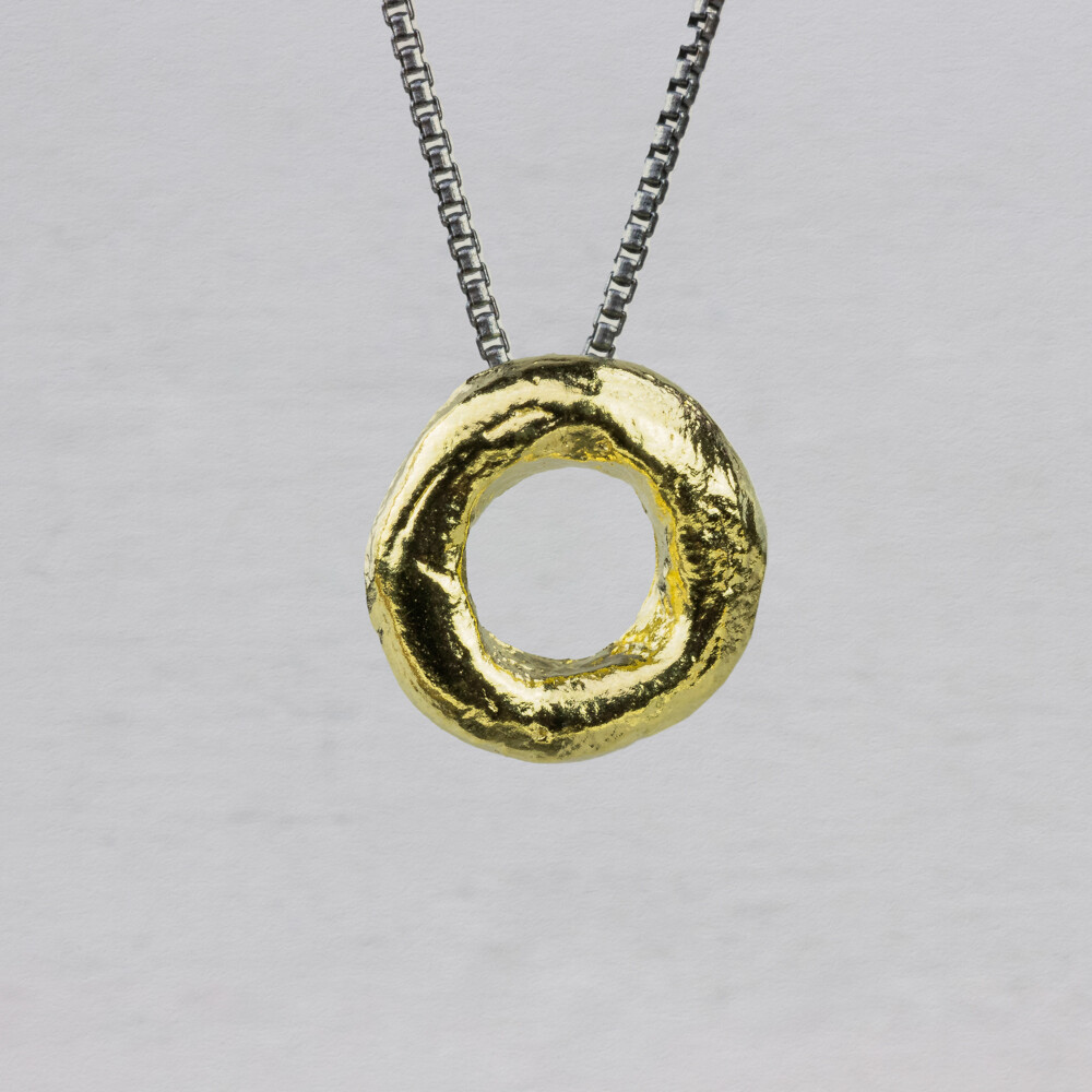 Collier gemaakt van 925 geoxideerd sterling zilver met daaraan een hanger wat lijkt op een donut gemaakt van zilver verguld. Combineer met de bijpassende oorhangers.