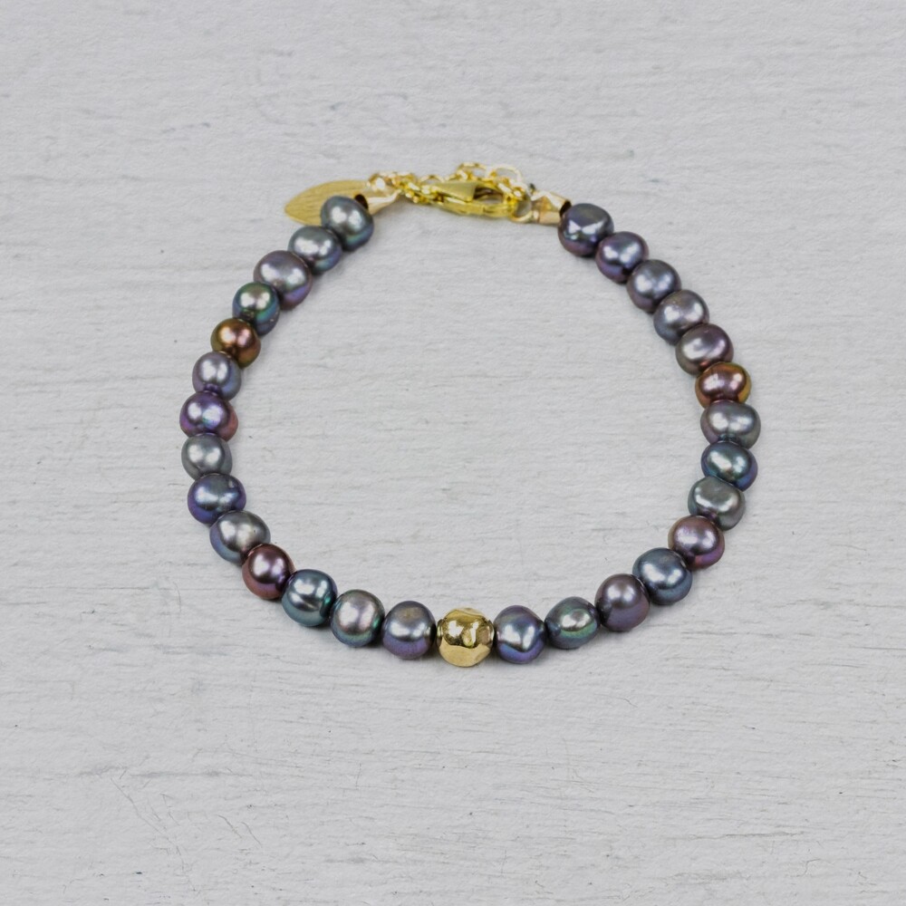 Armband gemaakt van Goldfilled in combinatie met grijze Parel. In het midden zit een Goldfilled balletje. De armband is verstelbaar waardoor je hem op een andere lengte kunt dragen. Combineer met een mooi collier oorbellen en een ring voor een complete look!
