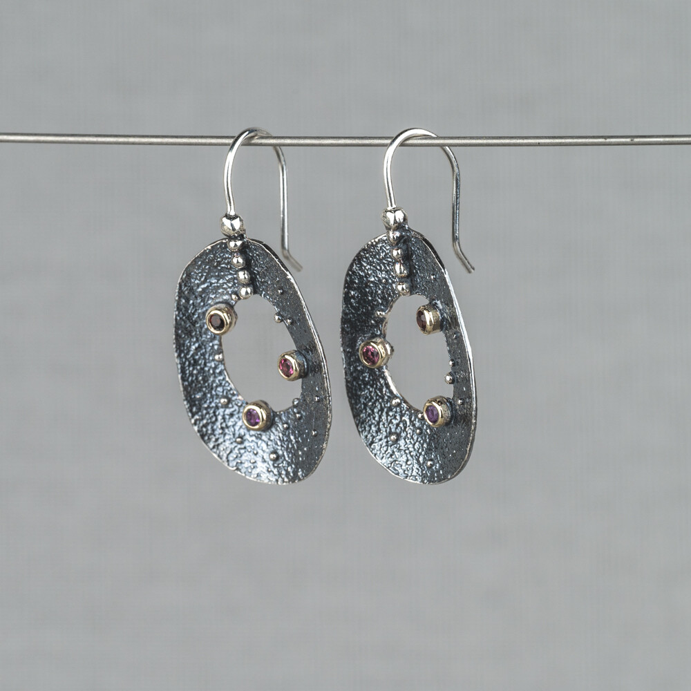 Oorhangers gemaakt van 925 (geoxideerd) sterling zilver met daarop 10 karaat kastjes met daarin de edelstenen Roze Toermalijn Granaat en Amethist. Lees alles over deze edelstenen via onderstaande button. Combineer deze oorbellen met het bijpassende collier en ring uit deze lijn.