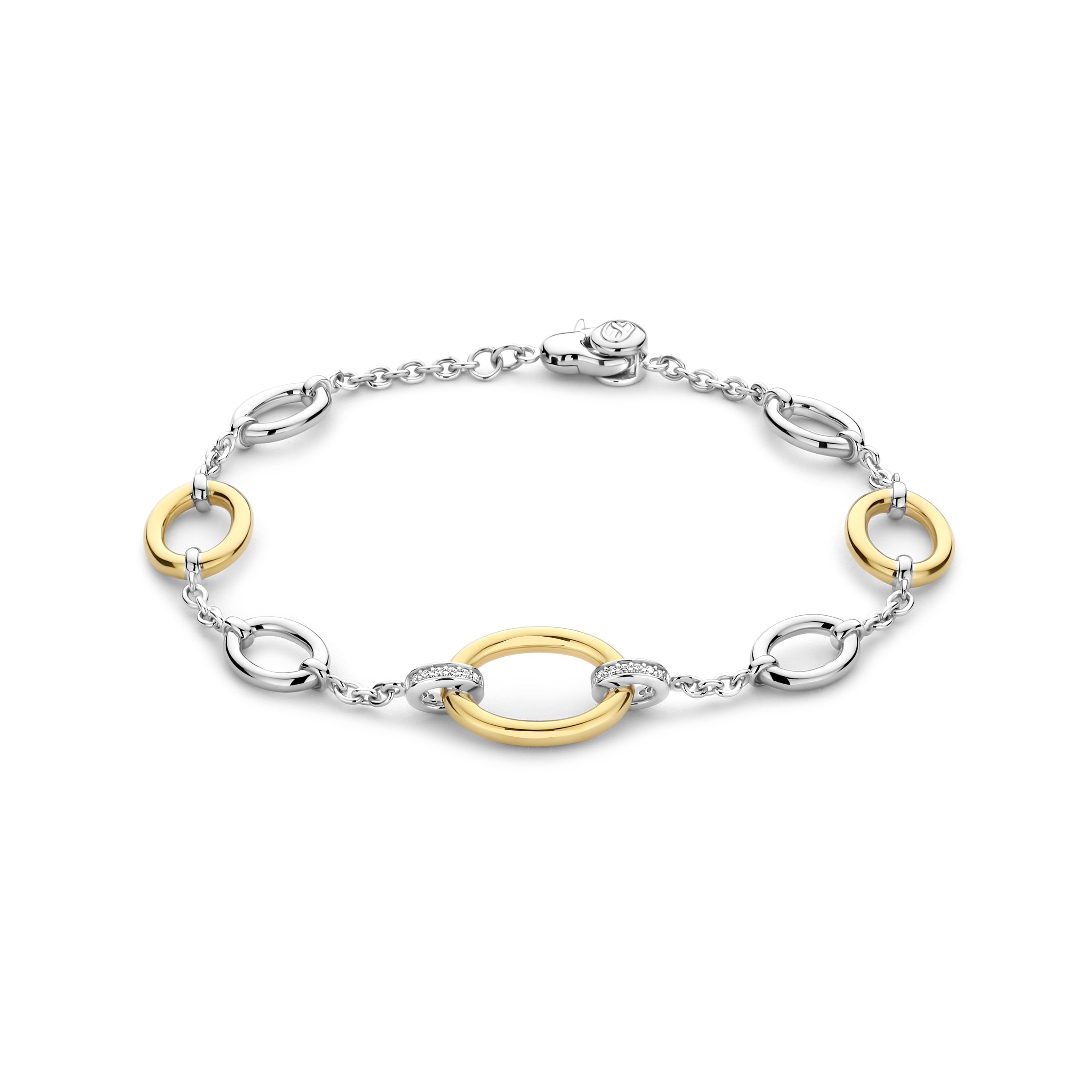 Vervaardigd uit premium 925 sterling zilver, toont de TI SENTO armband 23073ZY een harmonieuze mix van eigentijdse elegantie en tijdloze verfijning. Het afwisselende ontwerp heeft gedurfde vergulde schakels, gecombineerd met gepolijste zilvergekleurde ovalen, die allemaal met elkaar verbonden zijn door een delicate ketting. Het centrale ontwerp wordt geaccentueerd door twee goudkleurige schakels, omringd door pav�-set cubic zirconia ringen, die een sprankelende toets van schittering toevoegen.

De wisselwerking tussen warme gouden tinten en stralend zilver cre�ert de perfecte balans, die doet denken aan zonovergoten zomerdagen. Dit veelzijdige stuk past moeiteloos van casual draagstijl naar verfijnde avondlooks, wat het een onmiskenbaar accessoire maakt voor je sieradencollectie. Hypoallergeen en nikkelvrij, biedt het comfort en luxe, ontworpen om door elk seizoen heen te stralen.