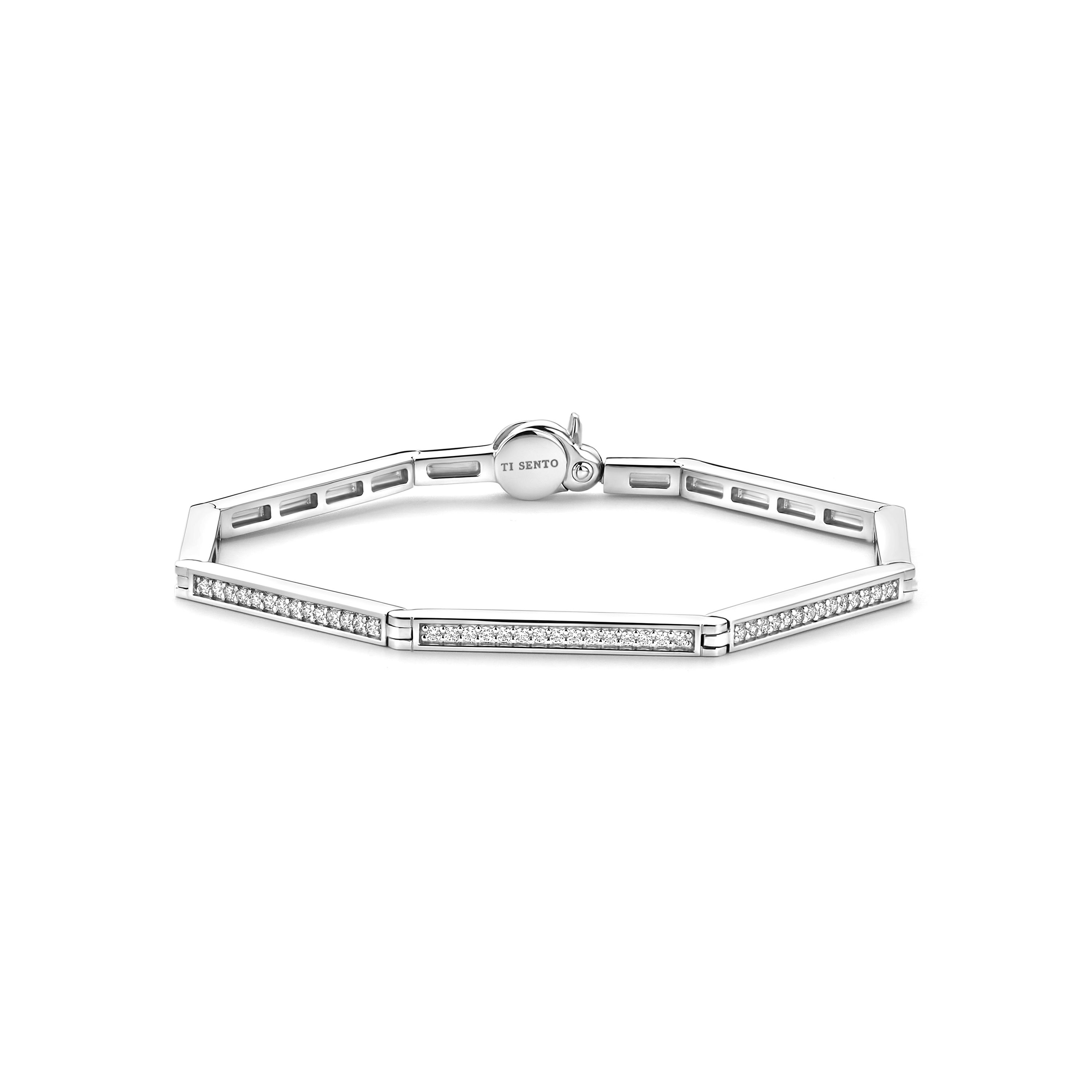 Breng hedendaagse elegantie naar een hoger niveau met de TI SENTO armband 23079ZI, een modern meesterwerk dat direct de aandacht trekt. Vervaardigd uit 925 sterling zilver en verguld, beschikt deze opvallende armband over een gedurfd geometrisch zeshoekig ontwerp, versierd met een pav� van fonkelende witte cubic zirconia.

De scherpe, hoekige lijnen van het zeshoekpatroon cre�ren een strakke en gestructureerde uitstraling, terwijl de zilveren kleur en de betoverende stenen een aura van verfijning en schittering toevoegen. Deze armband viert individualiteit en is een bewijs van de kracht van gedurfde, ingetogen elegantie.

Draag de armband solo voor een minimalistische statement of combineer het met andere TI SENTO sieraden voor een samengestelde en verfijnde look. Nikkelvrij en hypoallergeen, biedt deze armband ultiem comfort en kwaliteit, waardoor het een luxueuze en veelzijdige aanvulling is op je sieradencollectie.