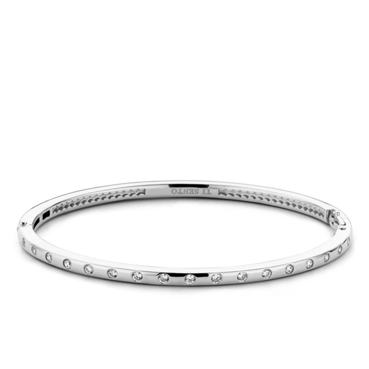 Een van de TI SENTO � Milano klassiekers in een nieuw jasje. Door de zirconia�s verder uit elkaar in een rechte lijn te plaatsen krijgt deze armband een modernere look. Doordat de armband zijn strakke lijnen heeft behouden is deze makkelijk te combineren met de andere toppers uit de TI SENTO � Milano collectie. Let ook op de details aan de binnenkant van het sieraad. Het opengewerkte zilver zorgt ervoor dat de zirconia�s nog mooier schitteren en beter tot hun recht komen. De armband is met veel zorg hand gemaakt volgens de goudsmid standaard. Het 925 sterling zilver is gerhodineerd waardoor de armband nog meer glans en extra bescherming krijgt.