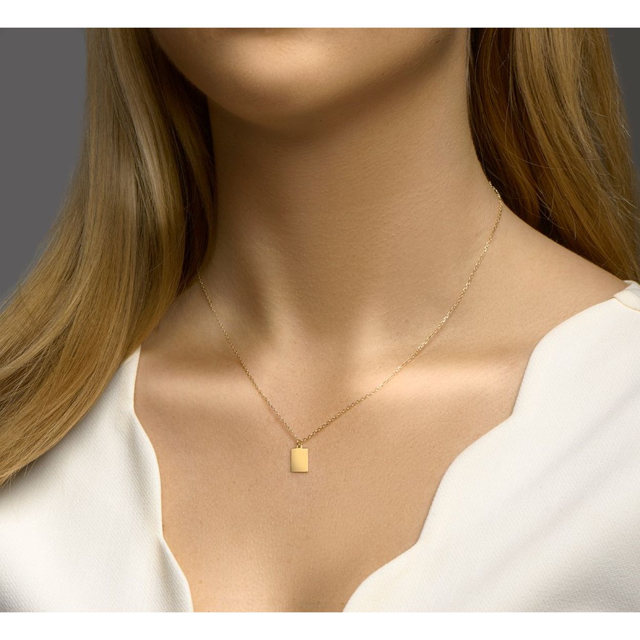 14k Geelgouden collier uitgevoerd met een rechthoekige hanger. Het collier heeft een draaglengte van 41cm met een extensie van 3cm. De hanger heeft een afmeting van 10x7mm.