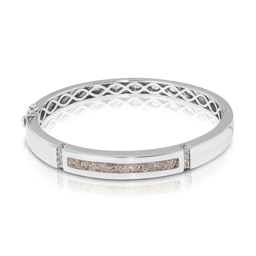 Zilveren as-armband met zirkonia. In het midden van de as-armband bevindt zich een brede streep waarin de het as/haar/moedermelk/melktandjes verwerkt wordt. De armband is voorzien van 2 extra veiligheidsslotjes.

Polsmaat opmeten:
Om de juiste armbandmaat te bepalen hebben we uw aangesloten polsmaat nodig (net achter de knokkel, richting de elleboog. Niet richting de hand). De polsmaat kunt u het beste opmeten met een meetlint. De standaard lengtes van deze armband zijn 57 mm, 60 mm en 62 mm.

 	Heeft u een polsmaat van 15 cm tot 16.5 cm, dan adviseren we armbandmaat 57 mm
 	Heeft u een polsmaat van 16.5+ cm tot 18 cm, dan adviseren we armbandmaat 60 mm
 	Heeft u een polsmaat van 18+ cm tot 19.5 cm, dan adviseren we armbandmaat 62 mm
Samenvatting:
Ook verkrijgbaar in goud met diamant
 	Standaard lengtes zijn 57 mm, 60 mm en 62 mm
 	Ook geschikt voor haar, moedermelk en melktandjes