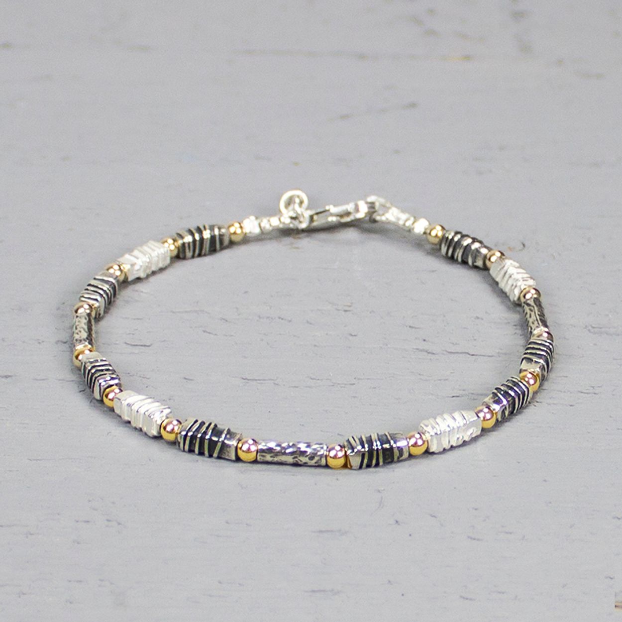 Armband uit de Touch of Gold-collectie van Jeh Jewels, gemaakt van 925 sterling zilver, geoxideerd zilver en gold filled. De schakels hebben allemaal een unieke stuctuur, wat deze armband zo bijzonder maakt. Combineer deze armband met het bijpassende collier. De glans van 925 sterling zilver maakt het een gewild edelmetaal voor de vervaardiging van sieraden. Het bestaat uit 92,5% puur zilver en 7,5% koper. Puur zilver is een zacht en buigzaam materiaal, het koper in 925 sterling zilver zorgt voor de stevigheid. De sieraden van Jeh Jewels zijn nikkel vrij. Gold filled komt uit Amerika en wordt daar al langer gebruikt voor de vervaardiging van sieraden met een "touch of gold" voor een betaalbare prijs. Het gold filled blijft op kleur, is slijtvast en de goudlaag is dik genoeg om lang te kunnen genieten van de warme uitstraling van goud. Gold filled wordt veelal ook goed verdragen door mensen die allergisch zijn voor andere metalen dan goud.