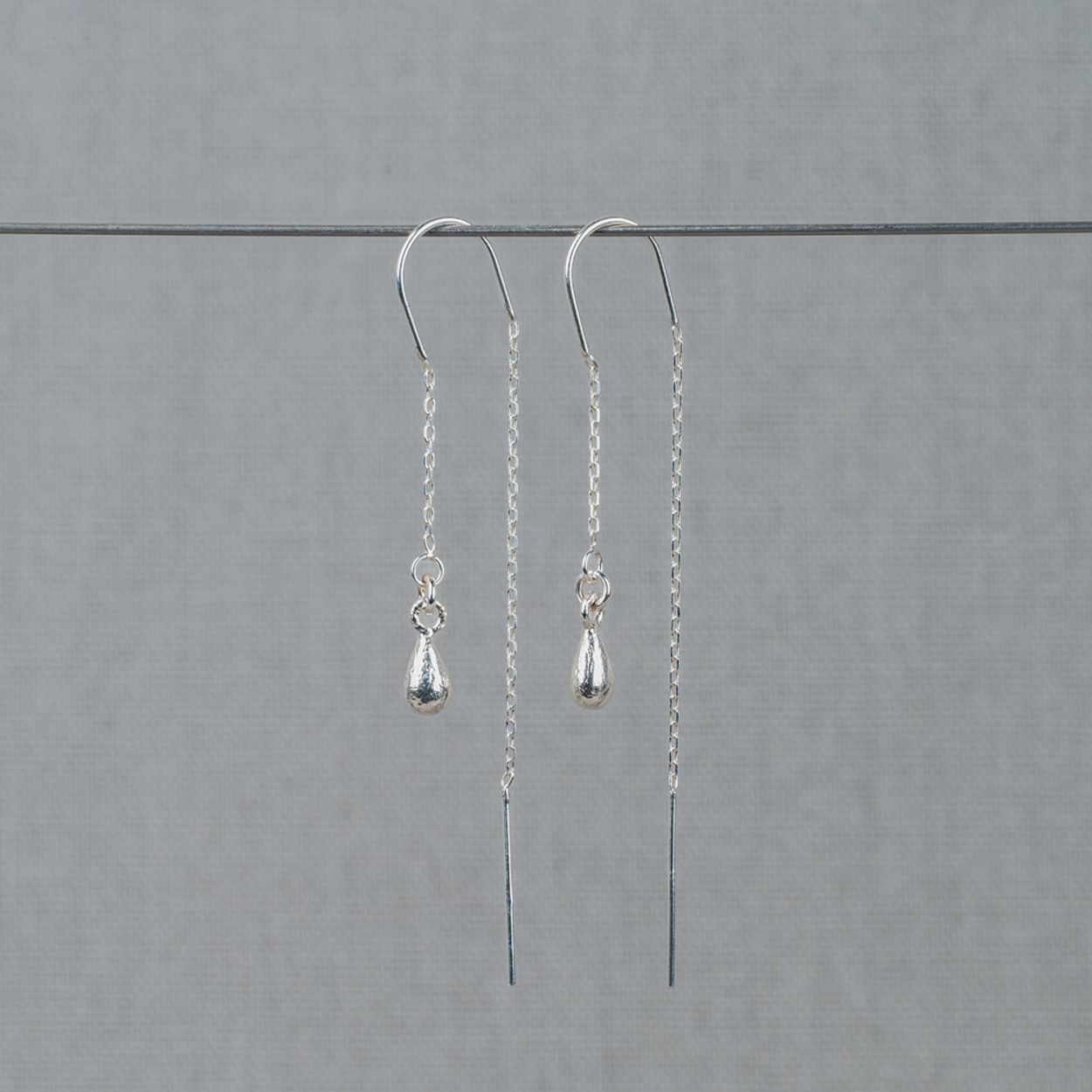 Doortrek oorbel gemaakt van 925 sterling zilver met daaraan een klosje van hetzelfde materiaal. 