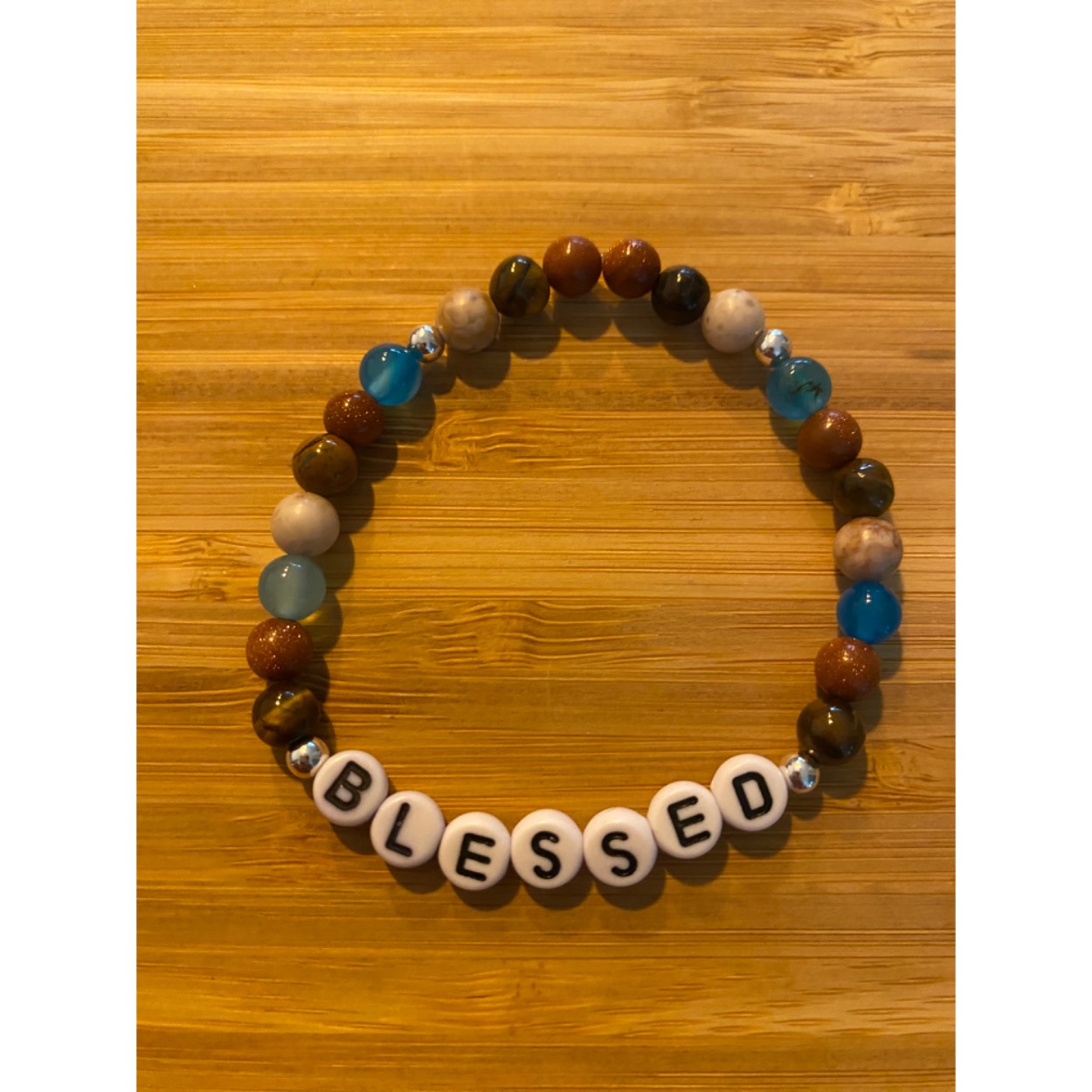 Lief armbandje met positieve tekst, tijgeroog, bruine goudsteen, blauwe agaat, zandsteen en zilveren ballen. 
Dit geschenkje is belangrijk voor jezelf om jezelf eraan te herinneren dat je gezegend bent met wie je bent. Je wordt blij als je het krijgt en even blij als je het weggeeft.
Armband kan op aanvraag met elke positieve tekst gemaakt worden( max 7 letters)
