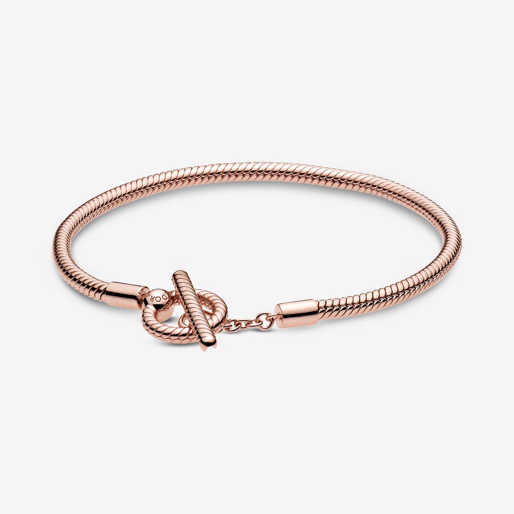 Breid je collectie uit met de Pandora Moments T-Bar Slangenschakel-armband. Dit met de hand in Pandora Rose (een met 14-karaats ros&eacute;goud vergulde unieke metaalmix) afgewerkte sieraad is een vernieuwde versie van de Pandora Moments-slangenschakelarmband. De armband heeft een t-barsluiting met dubbele cirkel. Haal de t-bar door de kleinste cirkel om er zeker van te zijn dat de armbandsluiting goed vast zit. Dit sieraad, voorzien van een slangenpatroon op de vaste delen van de armband, kan met 15 tot 20 Pandora Moments-bedels worden gedragen.