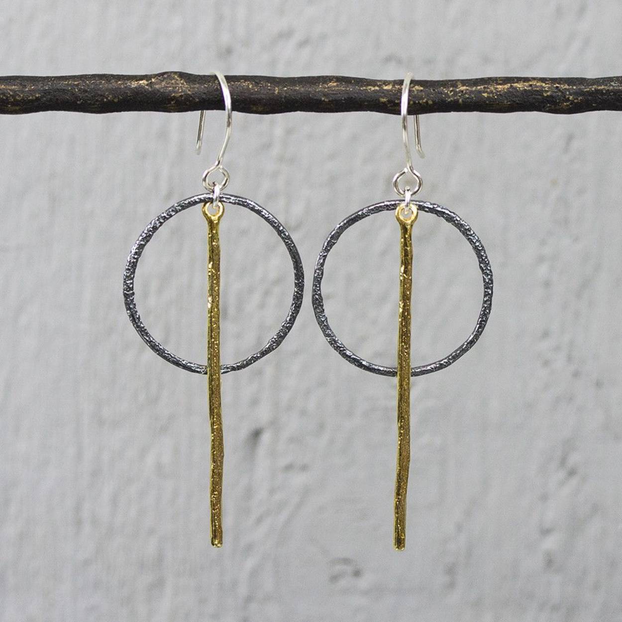 Oorhanger gemaakt van 925 sterling zilver, geoxideerd zilver en G14K zilver verguld. Aan de oorhanger hangt een geoixideerde cirkel, voor de cirkel hangt de vergulde pin. Materiaal: 14 karaat zilver verguld Vergulden is het bedekken van een voorwerp met een laagje goud. Dit artikel is door een goudbad gehaald wat ervoor zorgt dat het zilver volledig bedekt wordt met een laagje 14 karaats goud. Resultaat een mooie glanzende afwerking met een laagje echt goud wat ook wel silverplated of goldplated wordt genoemd.