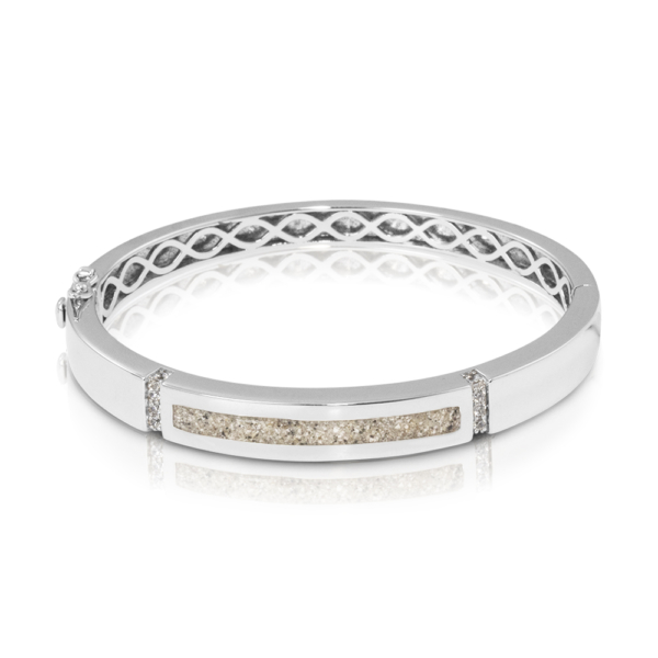 Zilveren as-armband met zirkonia. In het midden van de as-armband bevindt zich een brede streep waarin de het as/haar/moedermelk/melktandjes verwerkt wordt. Dit sieraad wordt zichtbaar aan de voorkant gevuld met as en wordt vermengd met onze speciale hars. U kunt dit helaas niet zelf vullen.
