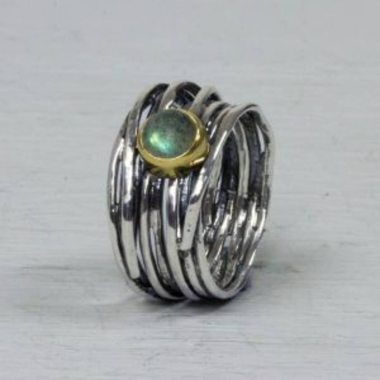 Ring gemaakt van 925 geoxideerd sterling zilver. De ring is met de hand gedraaid met bovenop in een kastje van 9 karaat een Labradoriet. 
