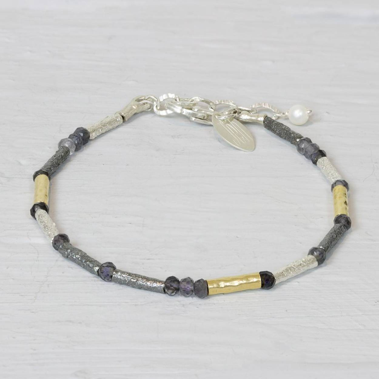Deze armband is gemaakt van buisjes van verschillende materialen. Er is zowel zilver, geoxideerd zilver, goldfilled en Ioliet gebruikt. Dit maakt deze armband zo makkelijk te combineren met elke outfit. 