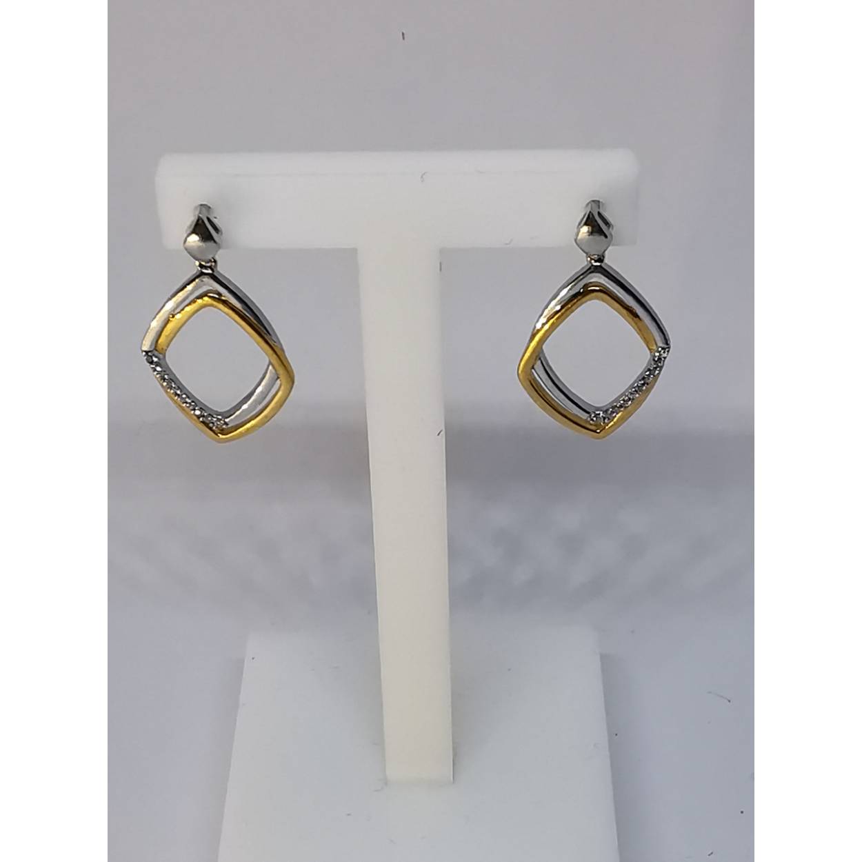 18 karaat bi-color gouden diamanten oorhangers. Geel gouden vierkant door een wit gouden vierkant gedeeltelijk bezet met diamanten.

Soort: Diamant
Slijpvorm: briljant
Karaat: 0.06
Helderheid: VS
Kleur: G
Aantal: 1