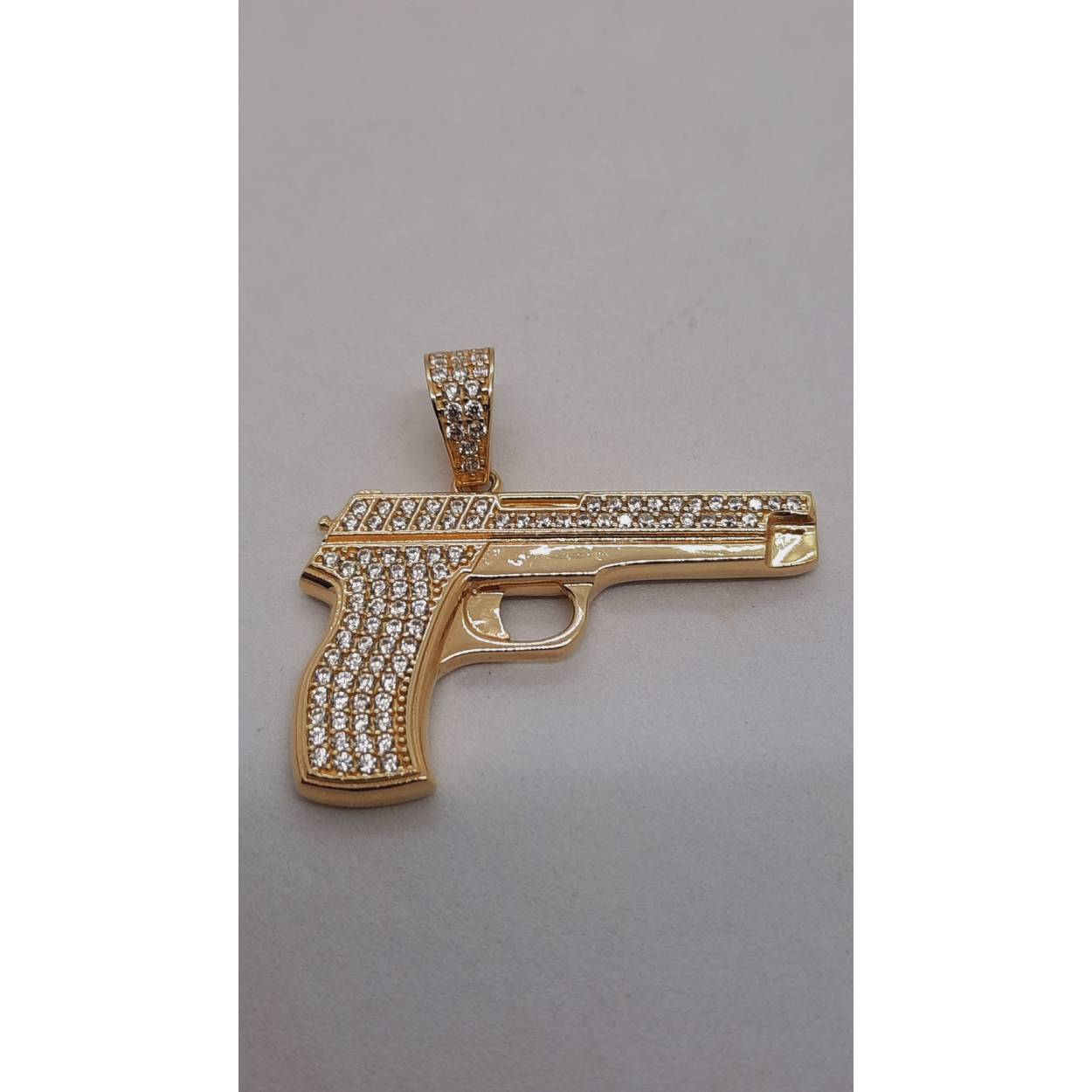 Deze prachtige Gouden Pistool Hanger met Zirkonia, modelnummer BREA-RDL-0004046, straalt luxe uit. Het bevat 14 karaat goud, weegt 7,54 gram en heeft een glanzende goudkleurige afwerking. Met een hoogte en breedte van 36mm is het een opvallend sieraad. Draag het aan een gouden ketting voor een elegante en extravagante uitstraling.