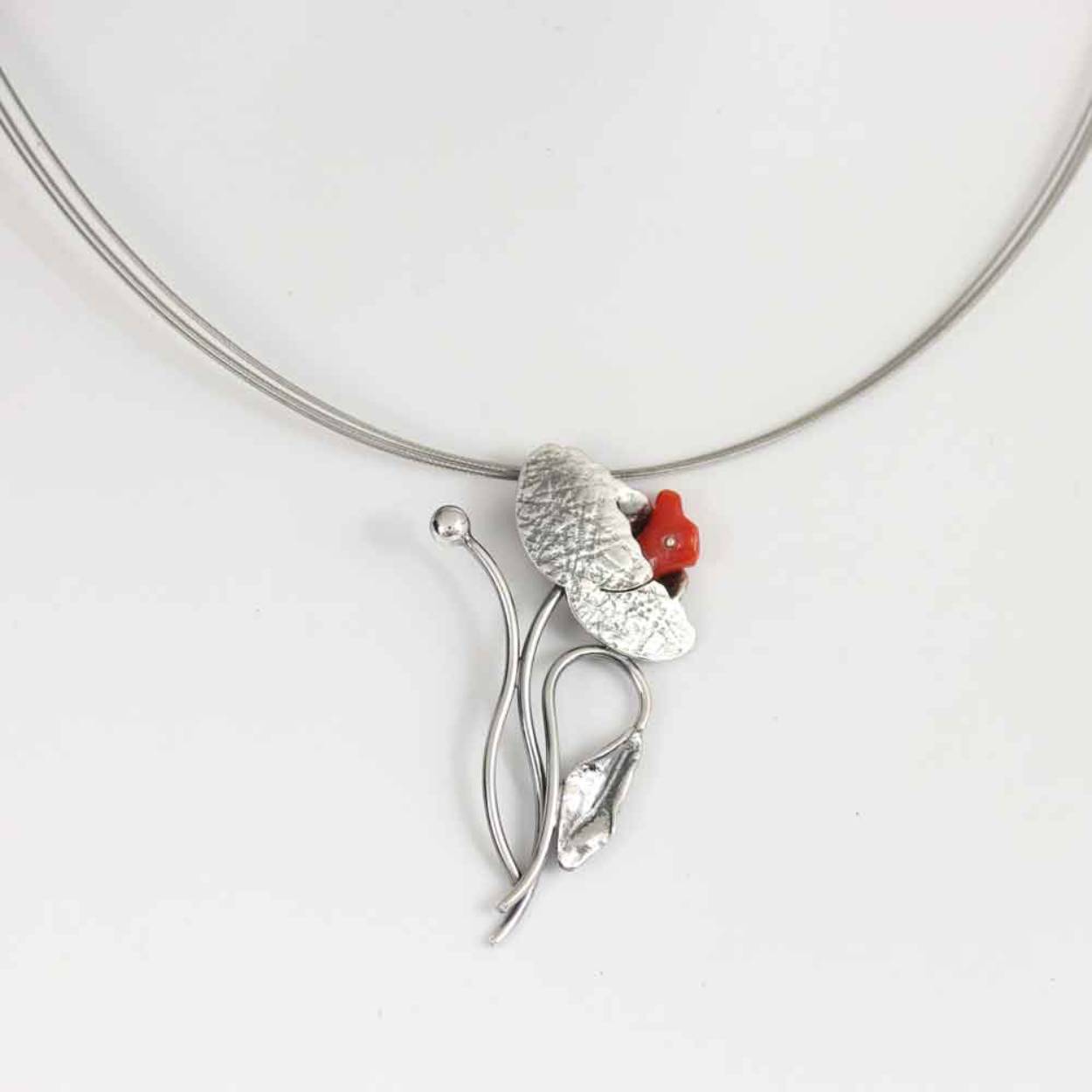 Buttner Schmuck handgemaakte sieraden vervaardigd in een klein atelier uit de Harz, zilveren hanger bloemmotief met bloedkoraal en staaldraadcollier. Vorm bloedkoraal kan variëren.