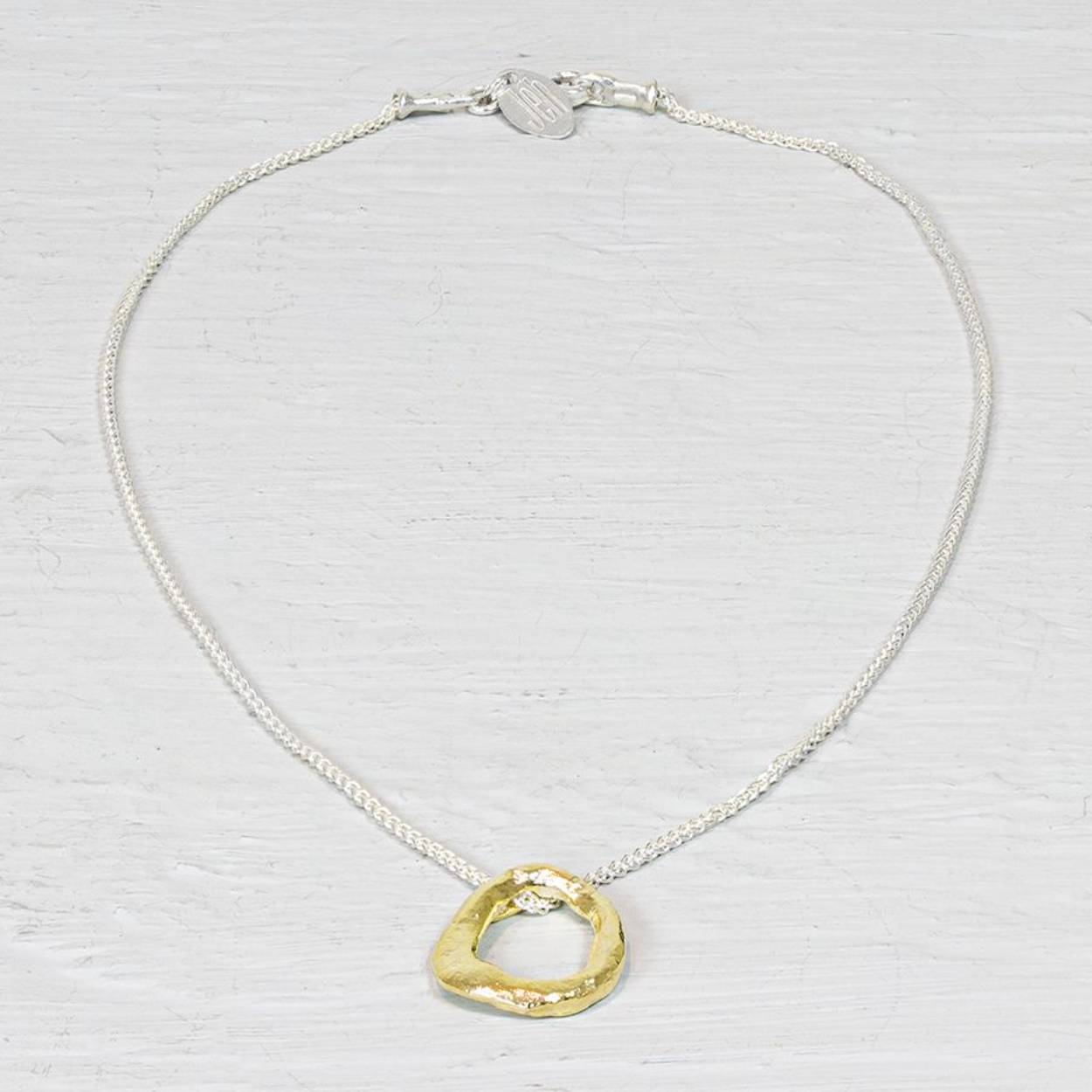 Collier van de najaarscollectie 2022 van Jéh Jewels met vergulde cirkel. Deze zilveren collier is uniek in zijn soort. De vergulde cirkel onderin is namelijk net niet helemaal rond. Dit geeft het zijn autentieke karakter en maakt 'm perfect te combineren.