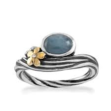 Deze sterling zilveren ring bevat een 10 x 8 mm aquamarijn steen, afgewerkt met een 14 kt. gouden bloemetje met een 0,005 crt. diamant briljant geslepen.
