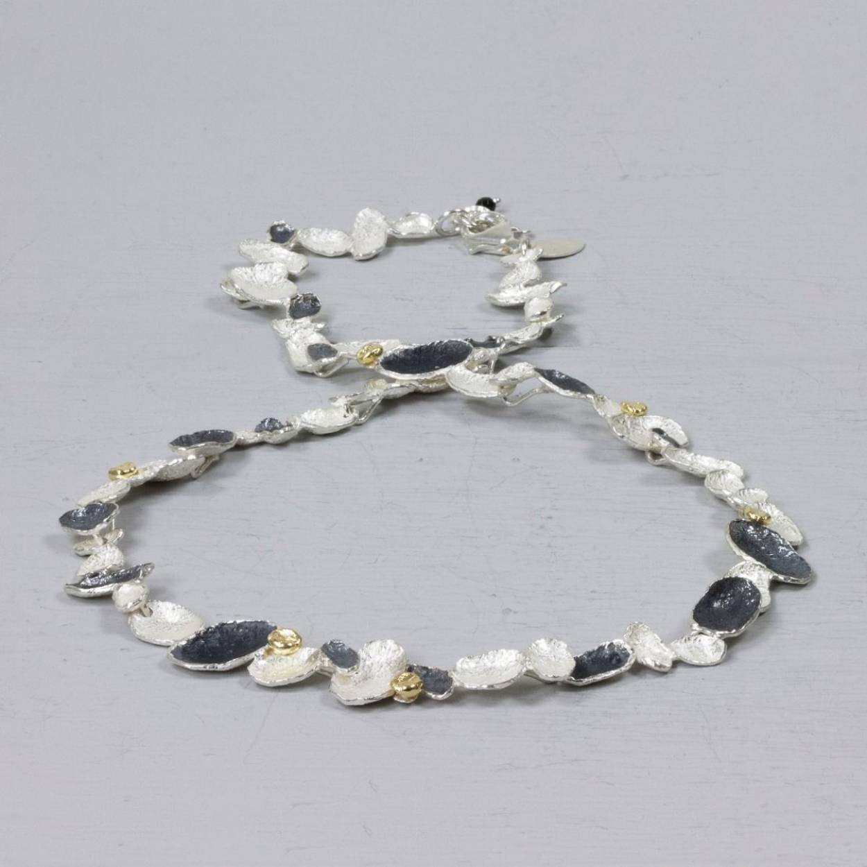Een collier waarbij je gelijk ziet dat hij van Jéh Jewels is. Gemaakt van 925 sterling zilver in combinatie met geoxideerd zilver en zilver verguld. Als je de losse schakels los bekijkt dan zijn het net de vleugels van een vlinder.

Materiaal: 925 sterling zilver
De glans van 925 sterling zilver maakt het een gewild edelmetaal voor de vervaardiging van sieraden. Het bestaat uit 92,5% puur zilver en 7,5% koper. Puur zilver is een zacht en buigzaam materiaal, het koper in 925 sterling zilver zorgt voor de stevigheid. De sieraden van Jéh Jewels zijn nikkel vrij.

Materiaal: Geoxideerd zilver
Op dit sieraad is gebruik gemaakt van geoxideerd zilver, dit is een oppervlakte bewerking. Het is mogelijk dat de geoxideerde laag na verloop van tijd door slijtage gaat vervagen.

Materiaal: Zilver verguld
Vergulden is het bedekken van een voorwerp met een laagje goud. Dit artikel is door een goudbad gehaald wat ervoor zorgt dat het zilver volledig bedekt wordt met een laagje goud. Resultaat een mooie glanzende afwerking met een laagje echt goud wat ook wel silverplated of goldplated wordt genoemd.
