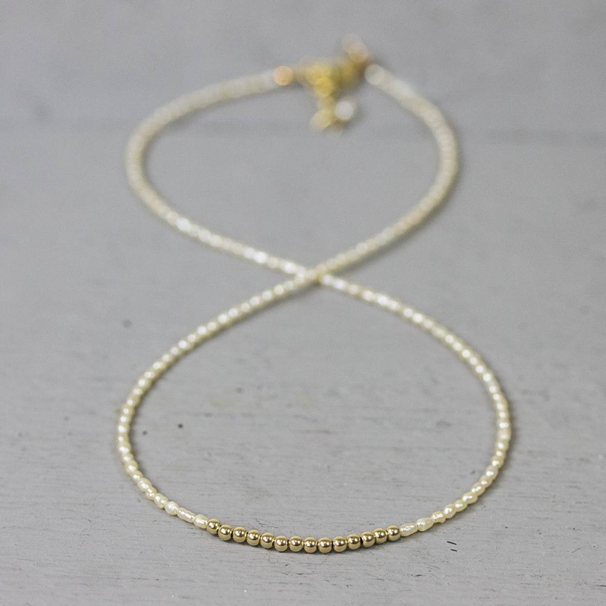 Collier gemaakt van offwhite parels met in het midden een rij Goldfilled bolletjes. Bij Jeh Jewels werken wij met echte edelstenen, dit zijn natuurlijke producten waardoor niet iedere steen hetzelfde is. Ieder sieraad is hierbij dus uniek. De kleur en structuur van de steen kan afwijken van de foto op de website.