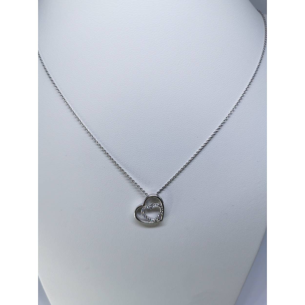 14 karaat wit gouden ankerschakel collier met diamanten hart hanger. De hanger bestaat uit een opengewerkt hart met daarin een kleiner hart bezet met diamanten geslepen in achtkant vorm.

Soort: Diamant
Slijpvorm: achtkant
Helderheid: WVS
Kleur: G
Aantal: 1