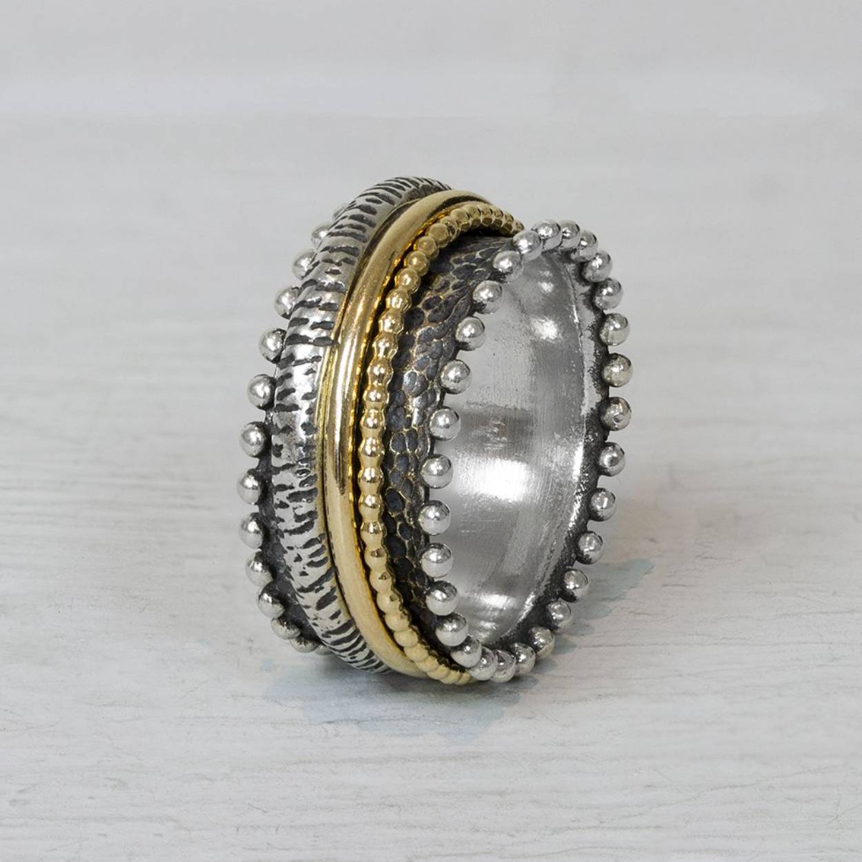 Ring model 20961 van Jéh Jewels gemaakt van geoxideerd zilver, en goldfilled. Deze ring heeft goldfilled bandjes die in het midden kunnen draaien. De bolletjes aan de zijkant maken deze ring extra leuk!

Materiaal: Geoxideerd zilver
Op dit sieraad is gebruik gemaakt van geoxideerd zilver, dit is een oppervlakte bewerking. Het is mogelijk dat de geoxideerde laag na verloop van tijd door slijtage gaat vervagen.

Materiaal: Goldfilled
Goldfilled komt uit Amerika en wordt daar al langer gebruikt voor de vervaardiging van sieraden met een "touch of gold" voor een betaalbare prijs. Het goldfilled blijft op kleur, is slijtvast en de goudlaag is dik genoeg om lang te kunnen genieten van de warme uitstraling van goud. Goldfilled wordt veelal ook goed verdragen door mensen die allergisch zijn voor andere metalen dan goud.

Materiaal: 925 sterling zilver
De glans van 925 sterling zilver maakt het een gewild edelmetaal voor de vervaardiging van sieraden. Het bestaat uit 92,5% puur zilver en 7,5% koper. Puur zilver is een zacht en buigzaam materiaal, het koper in 925 sterling zilver zorgt voor de stevigheid. De sieraden van Jéh Jewels zijn nikkel vrij.