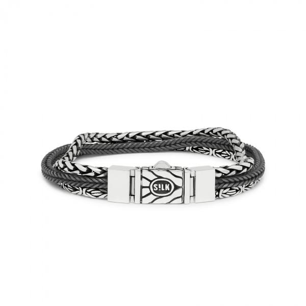 Met de RAW Editions sieraden heeft SILK een nonchalante look weten te creëren door het gebruik van nieuwe materialen in de handgemaakte sterling zilver collectie. Elk SILK-sieraad doorloopt een uitgebreid vakmanschap proces, resulterend in unieke massieve sterling zilveren ontwerpen voor rauwe mannen en vrouwen. Met de RAW editions introduceert SILK een aantal sterling zilveren armbanden gecombineerd met messing en zwart oxide, waarvoor speciale borsteltechnieken gebruikt werden voor een ‘worn style’ uiterlijk. De RAW editions ontwerpen zijn handgemaakt van pure metalen, messing en sterling 925 zilver.



Deze 283 RAW edition armband bevat géén messing. Deze armband bestaat in zijn geheel uit 925 sterling zilver, waarbij één streng gepolijst is, één streng mat gemaakt is met een speciale borstel techniek en één streng bedekt is met zwart oxide. Deze armband heeft daardoor een rauw gedragen uiterlijk. Het zwart is "made to fade", wat betekend dat het zal krassen en vervagen op een manier die je eigen verhaal verteld. Juist deze RAW worn-style look is wat deze armbanden zo uniek maakt!



Tof detail aan deze armband is dat deze sluit middels een omkeerbaar structuur slot, welke daardoor aan twee zijde gedragen kan worden, desgewenst met het logo naar voren of met het logo naar binnen.