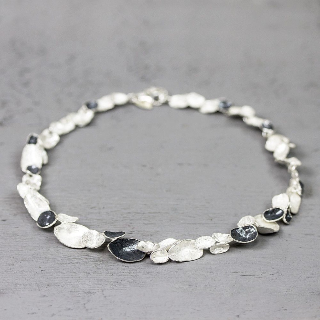 Collier gemaakt van 925 sterling zilver en geoxideerd zilver. De verschillende delen zilver lijken op schelpen.

Materiaal: 925 sterling zilver
De glans van 925 sterling zilver maakt het een gewild edelmetaal voor de vervaardiging van sieraden. Het bestaat uit 92,5% puur zilver en 7,5% koper. Puur zilver is een zacht en buigzaam materiaal, het koper in 925 sterling zilver zorgt voor de stevigheid. De sieraden van Jéh Jewels zijn nikkel vrij.
