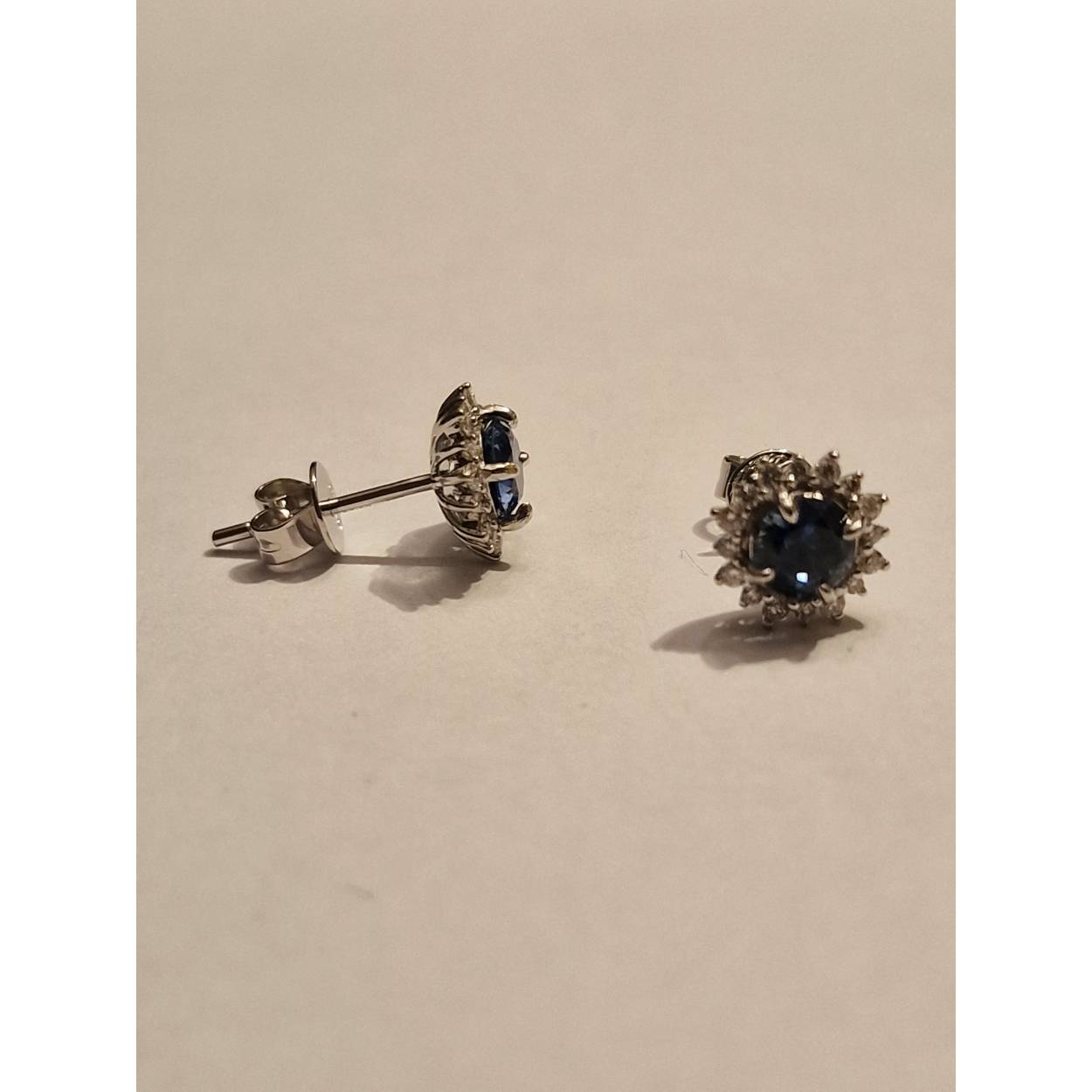 14k witgouden rozetoorknop met ronde saffier van 5mm en diamant Middensteen is een Montana (USA) Saffier, met een briljant slijpsel . Montana Saffier heeft een aparte kleur blauw en is in tegenstelling tot de meeste andere saffier bijna altijd onbehandeld( No Heat)