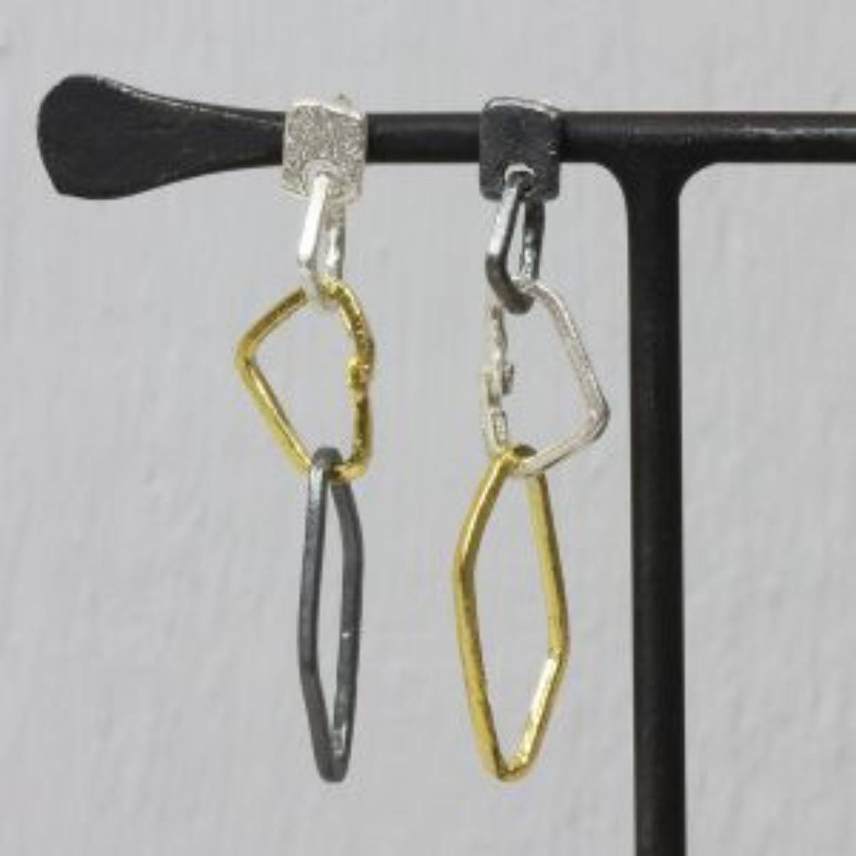 Oorbel assymetrische schakels grof drie kleuren, de oorbel is gemaakt van 925 sterling zilver, in combinatie met geoxideerd zilver en zilver verguld. De oorbellen worden met een steker in het oor bevestigd.