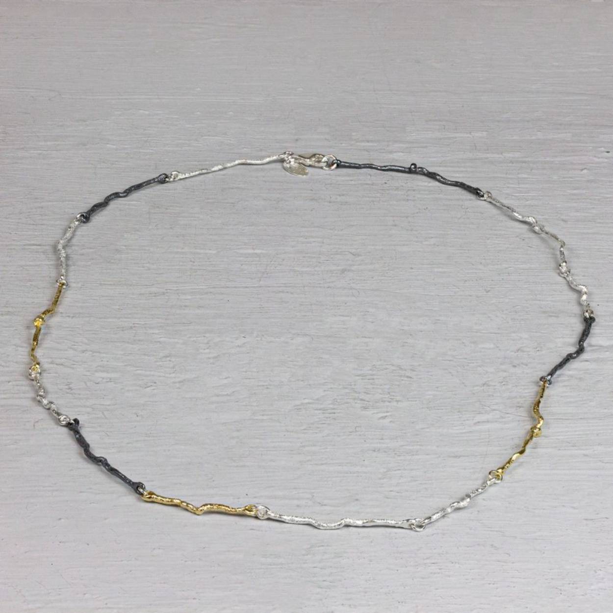 Collier van de najaarscollectie 2022 van Jéh Jewels met drie kleuren takjes. Dit collier is een combinatie van drie verschillende kleuren zilver. Namelijk zilver, geoxideerd en verguld zilver. De vorm van de schakels heeft iets weg van kleine takjes. Een perfect collier voor in het najaar. 