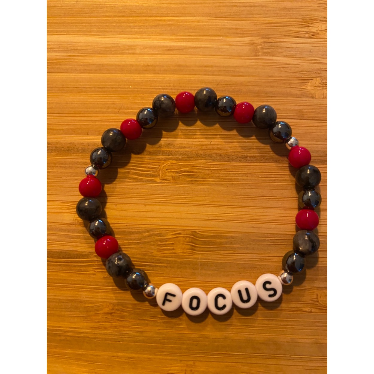 Lief armbandje met positieve tekst.Hematiet, grijze zandsteen en bloedkoraal en zilveren ballen. 
Dit geschenkje is belangrijk voor jezelf om jezelf eraan te herinneren dat je je focus niet moet verliezen en dat alles mogelijk is als je in jezelf gelooft. Je wordt blij als je het krijgt en even blij als je het weggeeft.
Armband kan op aanvraag met elke positieve tekst gemaakt worden( max 7 letters)