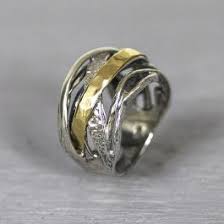 Ring gemaakt van 925 sterling zilver, geoxideerd zilver en 9 karaat. Deze ring is anders dan de gebruikelijke ringen, in plaats van bewegende bandjes heeft deze ring bogen.