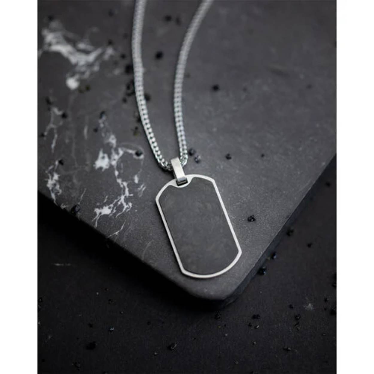 De Bellum Silver halsketting is gemaakt met een 2mm zilverkleurige vossenstaartketting en heeft een hanger uit gesmeed carbon. De Latijnse naam 'Bellum' betekent 'oorlog' en verwijst naar de vorm van de hanger, die vaak door moderne soldaten wordt gedragen met hun persoonlijke gegevens op.

De ketting is 58cm lang en wordt geleverd met een verlengstukje van 6cm, waardoor je zeker weet dat hij altijd past.

De hanger is gemaakt uit gesmeed carbon, een exclusief materiaal dat ook wordt gebruikt in superwagens, raceboten en de ruimtevaart. De verhouding tussen vermogen en gewicht van dit materiaal is buitengewoon en het wordt gemaakt van koolstofvezel die onder hoge druk wordt gevormd. Dit geeft de carbon hanger zijn zilver-grijs-zwarte tinten.