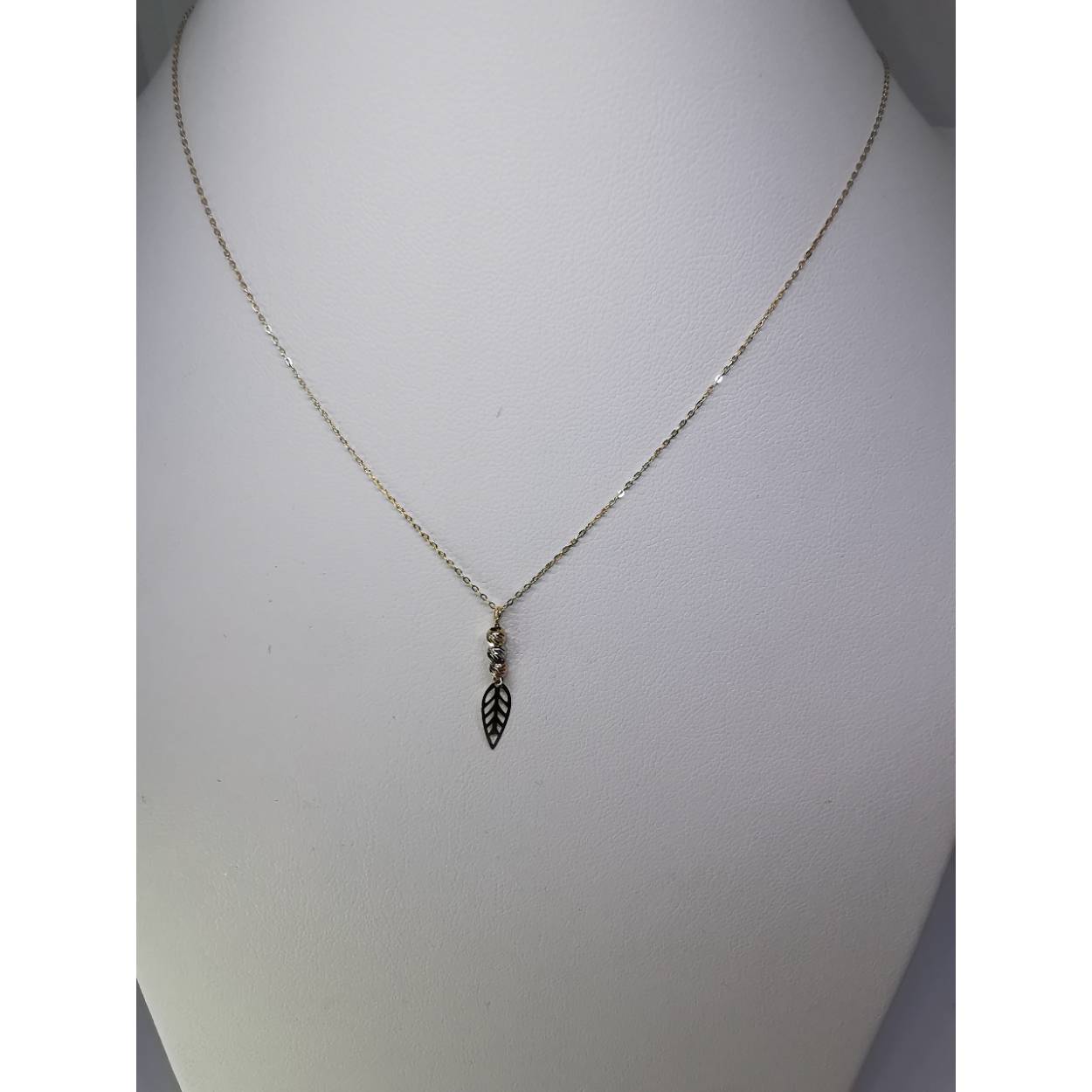 14 karaat geel gouden fijne schakel collier met hanger. De hanger bestaat uit drie doreka kraaltjes mat daaronder een veertje.

0.91 gram
43 - 45 cm lang (verstelbaar)
